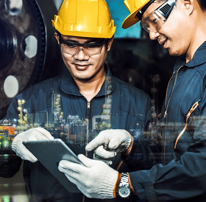 2 men in their work clothes and helmet looking at the tablet.